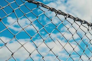A close-up of a chain link fence with a cloudy sky in the background. photo