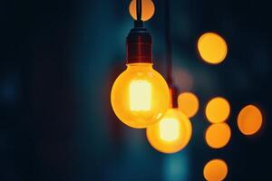A single glowing light bulb hanging in front of a dark background with other out-of-focus light bulbs behind it. photo