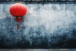 A red Chinese lantern hanging on a weathered gray wall. photo