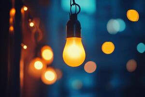 A single lightbulb hangs from a string of lights, glowing brightly against a blurry background of bokeh. photo