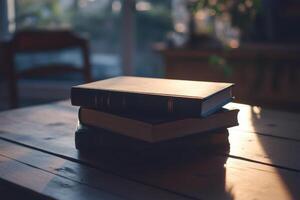 A stack of three hardcover books on a wooden table with warm, natural light shining down on them. photo