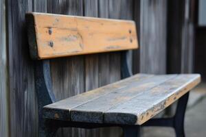 A weathered wooden bench sits against a wooden wall. photo
