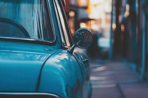 Close up of a blue vintage car's side mirror, parked on a city street with warm golden light in the background. photo