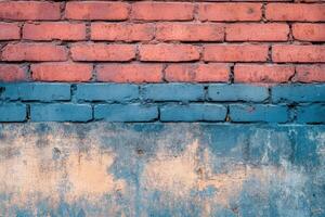 A weathered brick wall painted blue and red with a concrete base. photo