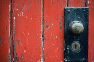Old weathered red wooden door with brass doorknob and keyhole. photo
