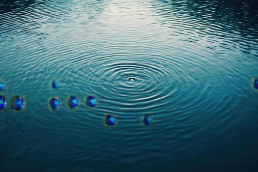 Ripples on a still blue lake with a small group of shimmering blue bubbles. photo