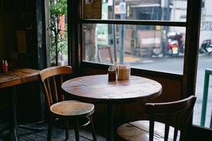 A rustic wooden table with two chairs sits near a window in a cozy cafe. photo