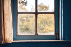 A weathered blue windowpane with a view of blurry trees through the glass. photo