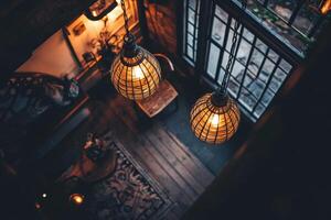 Two hanging globe lights illuminate a cozy living room with a wooden floor, rug, and a window. photo
