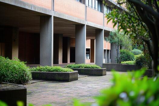 Concrete pillars and a walkway with greenery lead to a brick building. photo