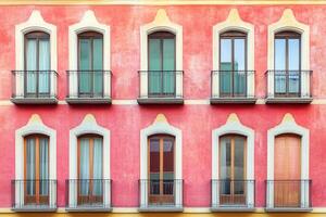 Pink building facade with eight windows and balconies. photo