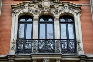 Ornate balcony with three arched windows on brick building. photo