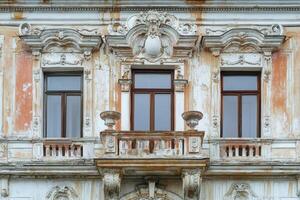 Ornate facade of an old building with three windows and a balcony. photo