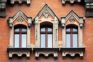 Three arched windows with ornate trim on a brick building. photo