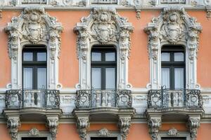 Three ornate windows with balconies on an old building. photo