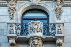 Ornate balcony with wrought iron railing and arched window on a historic building. photo