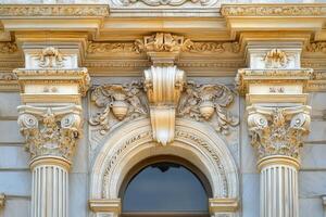 Ornate architectural detail above a doorway with columns and an arched window. photo