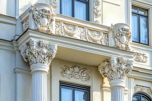 Ornate balcony with white pillars and intricate carvings on a building facade. photo