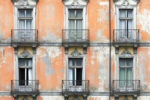 Six windows and balconies on a weathered orange building. photo