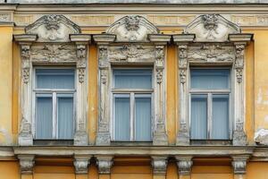 Three ornate windows on a yellow building facade. photo