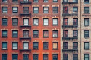 Two brick buildings with windows and fire escapes. photo