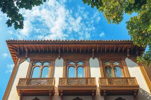 White building with wooden balconies and windows against blue sky. photo