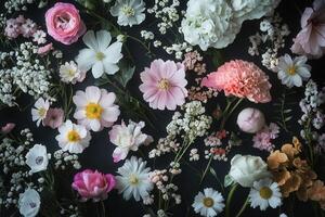 Flat lay of pastel pink, white, and peach flowers on a dark background. photo
