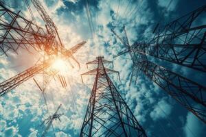 Low angle view of power lines against a cloudy sky with the sun shining through. photo
