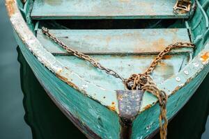 Weathered green rowboat with chain. photo