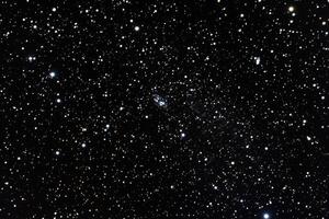 A faint, fuzzy galaxy visible amongst a field of stars. photo