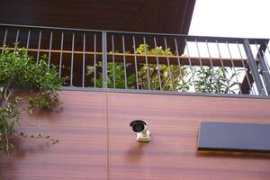 A modern balcony view showcasing a security camera and lush greenery in a stylish setup photo