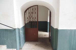 A Beautiful Rustic Archway Accompanied by an Intricate Iron Gate Located in an Old Stairwell photo