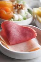A beautifully arranged plate featuring fresh deli meats alongside an array of colorful salads photo