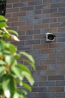 A visibly damaged security camera is mounted on a wall with its bracket still attached photo