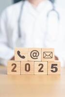 Contact Us concepts. Happy New Year 2025 with Wood block of Email, call Phone and Website Address sign against Doctor background. Healthcare Customer support hotline, health and communication concept photo
