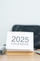 2025 Year Calendar on table with laptop computer during working and writing in office. countdown, Happy New Year, Resolution, Year End and New Start and Goals Plan Action Concept photo