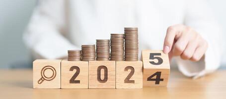 2024 end year to Happy New Year 2025 with coins money stack growing with magnifier glass. Money saving, Inflation, tax, cash flow, Job search, hiring and research development concepts photo