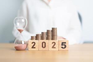 Happy New Year 2025 with hourglass and coins stack arrangement. Money Saving for Future Plan, Retirement fund, Pension, Investment, Wealth Business, Financial and countdown concepts photo