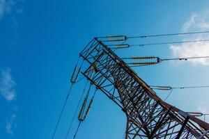 Close-up view of an electric tower with a beautiful blue sky background. Industrial engineering concept. Iron structure for high-voltage electrical engineering. photo