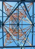 Close-up view of an electric tower with a beautiful blue sky background. Industrial engineering concept. Iron structure for high-voltage electrical engineering. photo