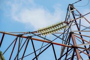 Close-up view of an electric tower with a beautiful blue sky background. Industrial engineering concept. Iron structure for high-voltage electrical engineering. photo