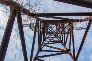 Close-up view of an electric tower with a beautiful blue sky background. Industrial engineering concept. Iron structure for high-voltage electrical engineering. photo