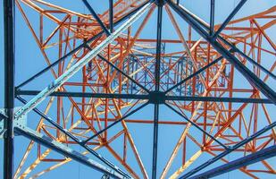 Close-up view of an electric tower with a beautiful blue sky background. Industrial engineering concept. Iron structure for high-voltage electrical engineering. photo