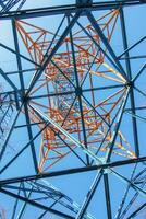 Close-up view of an electric tower with a beautiful blue sky background. Industrial engineering concept. Iron structure for high-voltage electrical engineering. photo