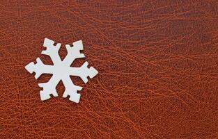 White Snowflake Model On Elegance Brown Leather Surface Copy Space Image. Snowflake Design For Greeting Card And Wallpaper Stock Photo