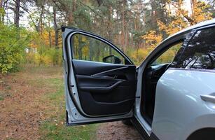 Opened Door Of A Car Parked On A Forest Clearing. Outdoor Car Travel Stock Image. SUV Stay In The Autumn Forest photo