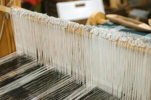 Traditional loom weaving craftsmanship with threads and textile patterns for artisanship photo