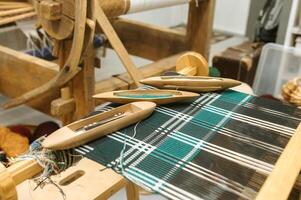 Traditional loom weaving with wooden shuttles and colorful textile patterns photo