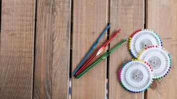 Set of colorful crochet hooks and several wheels of sewing pins arranged neatly on a wooden surface. photo
