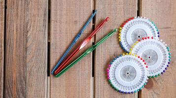 Set of colorful crochet hooks and several wheels of sewing pins arranged neatly on a wooden surface. photo
